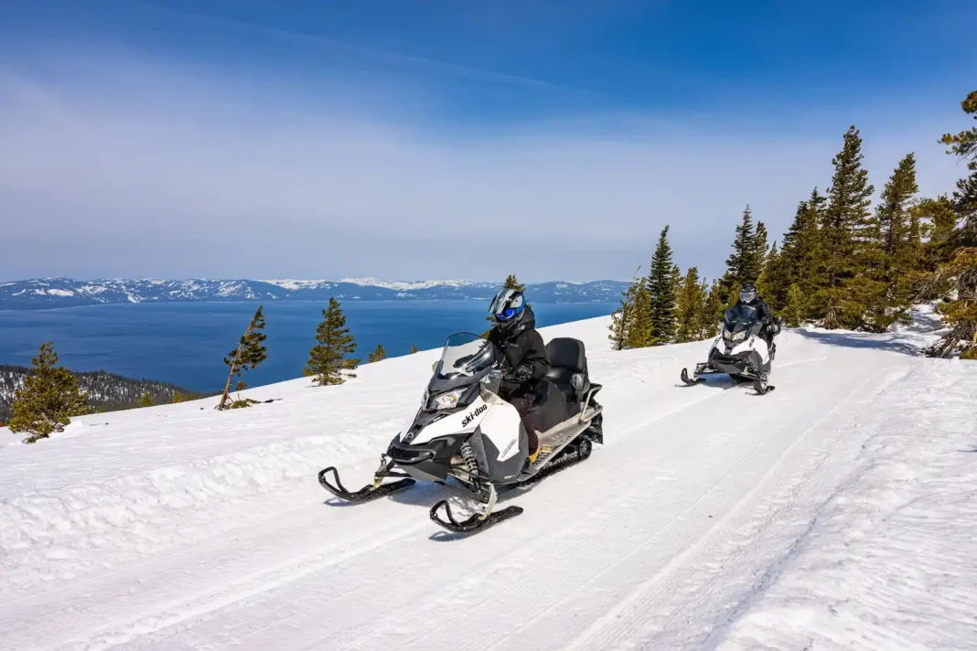 People riding snowmobiles above Lake Tahoe