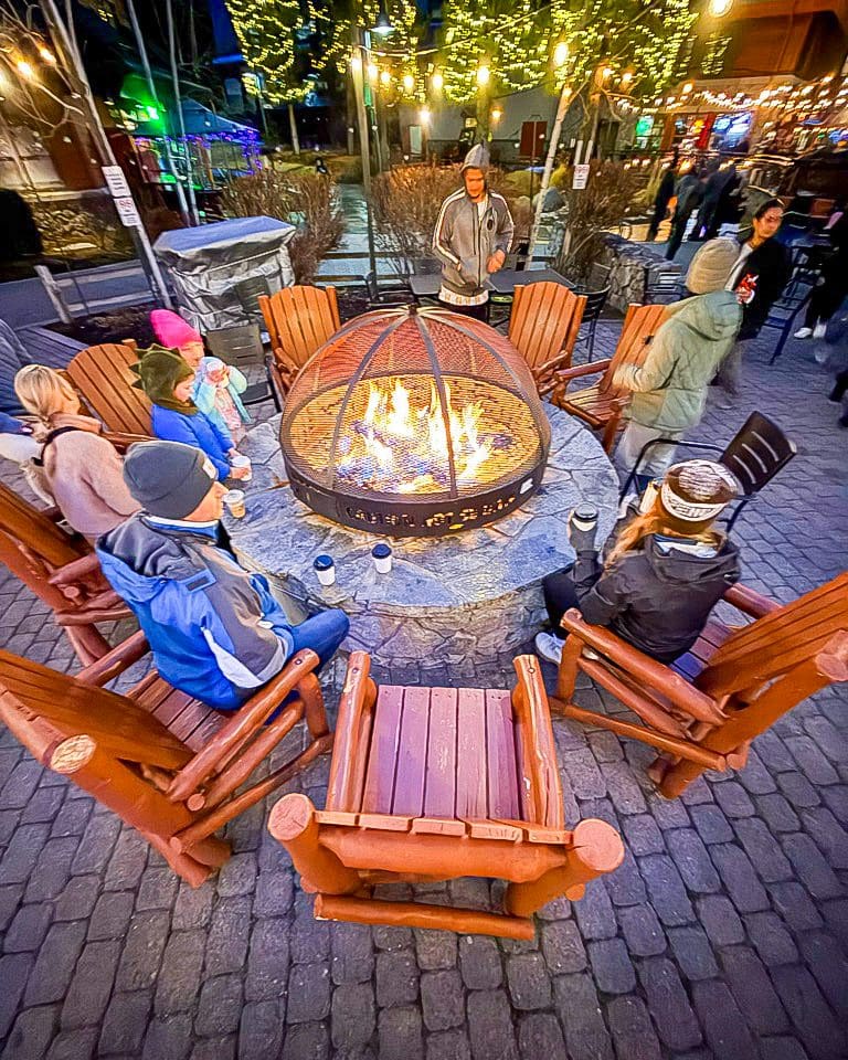Friends and kids gathered around a fire pit during apres ski